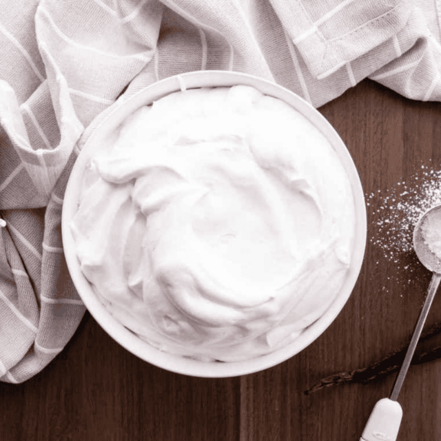 cream in a bowl with mixing paddle and powdered sugar on the side