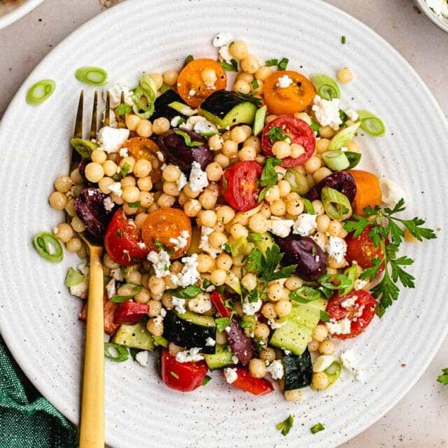 Dressed couscous and vegetables on plate with fork.