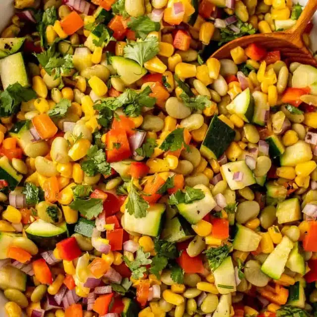 Close up of side dish with corn, peppers, zucchini, and beans.
